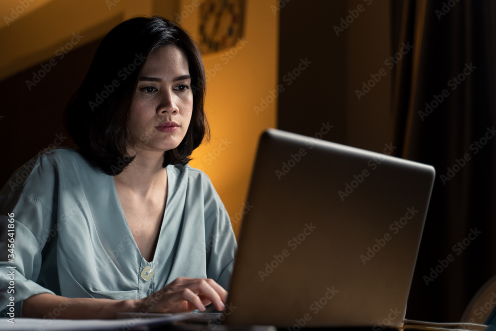 Asian business woman does overtime working from home in living room at late night due to covid19 pan