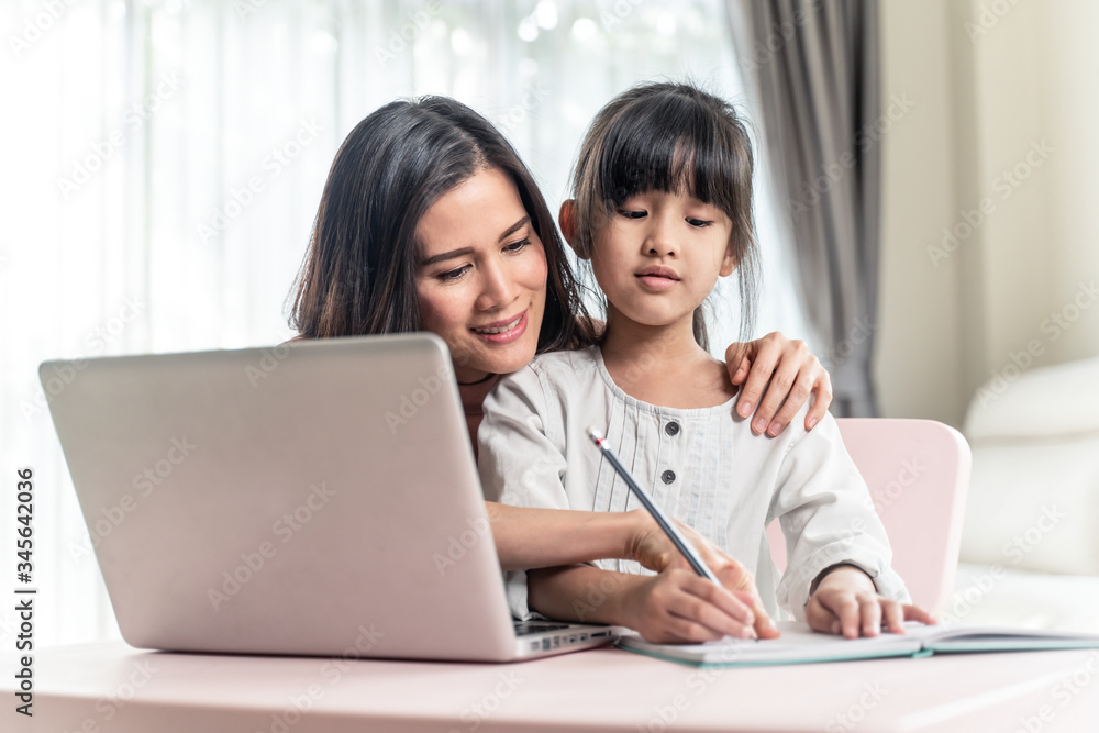 Homeschool Asian young little girl learning online and does homework by using internet on computer w