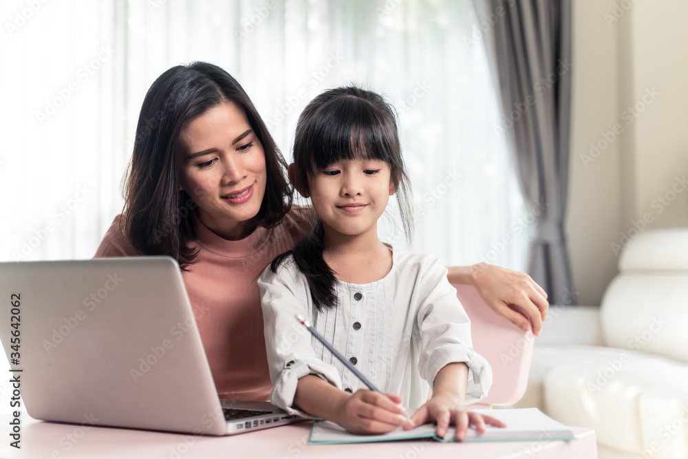 Homeschool Asian young little girl learning internet online class and do homework by using computer 