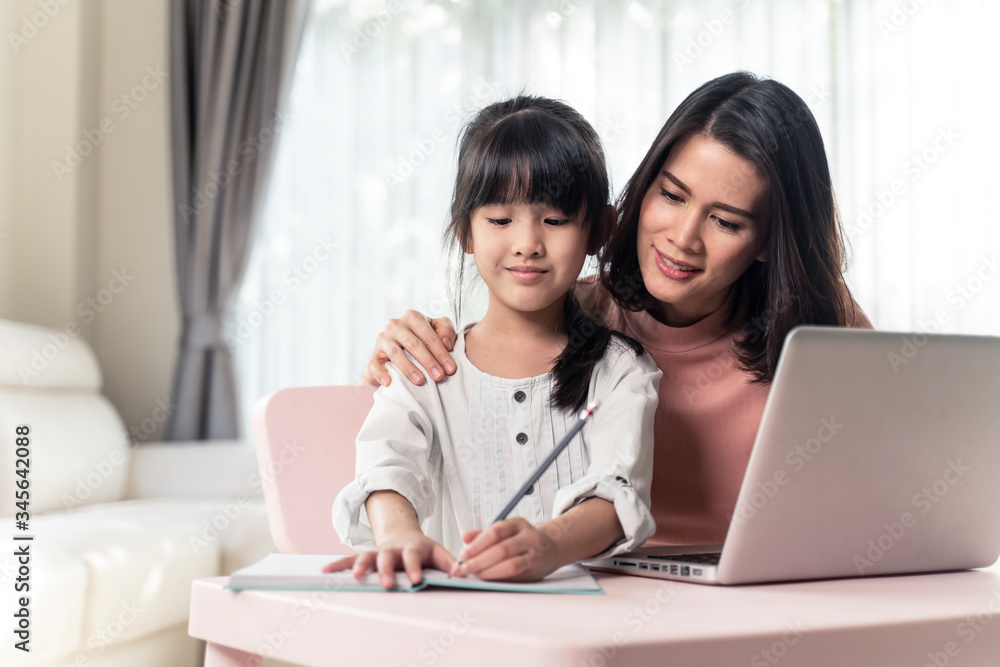 Homeschool Asian young little girl learning internet online class and do homework by using computer 