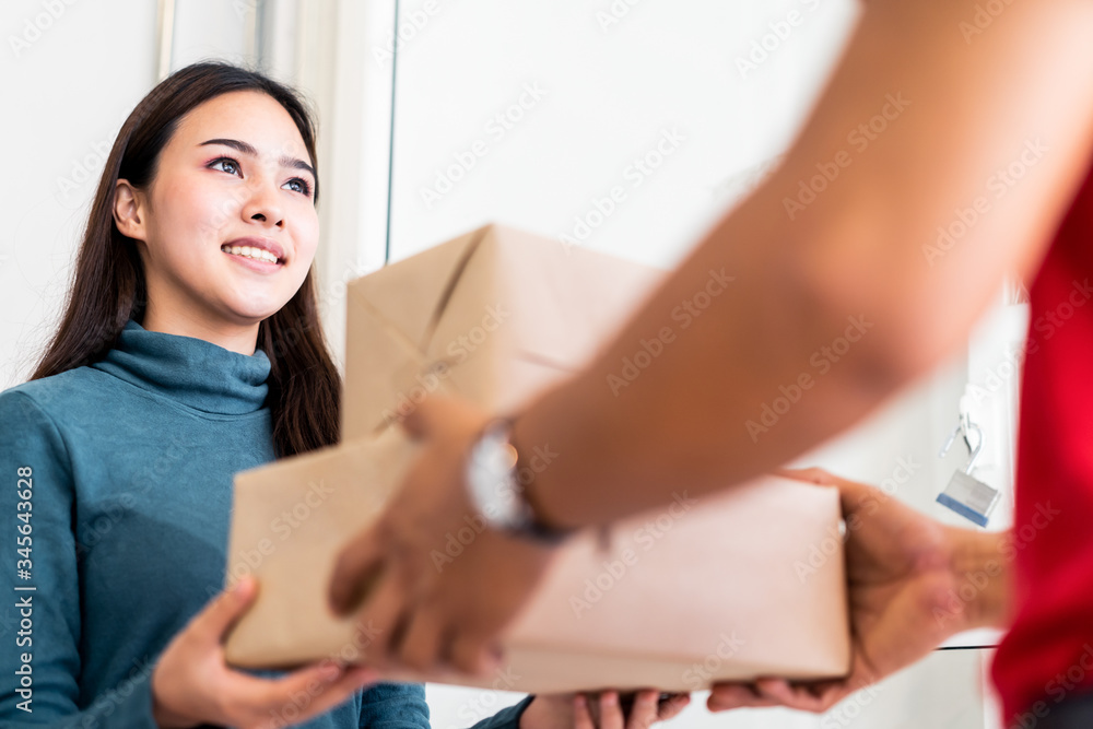 邮差送包裹回家。年轻的亚洲可爱女孩收到来自p的两个盒子