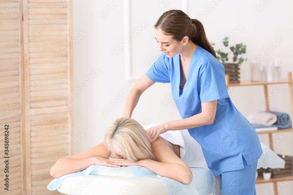 Massage therapist working with female patient in medical center