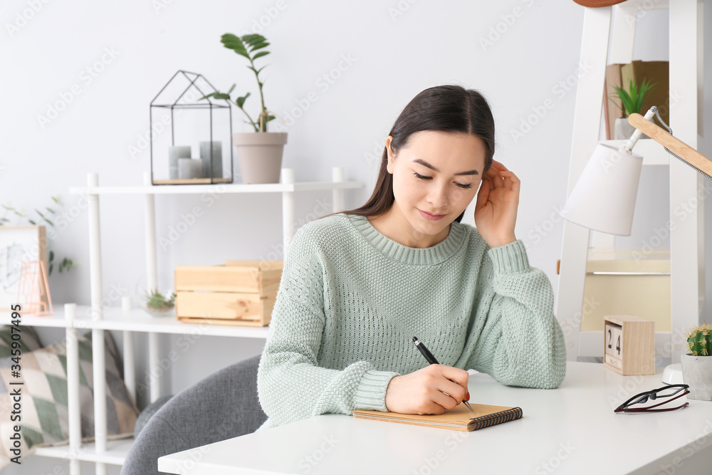 Portrait of beautiful young woman writing something in notebook