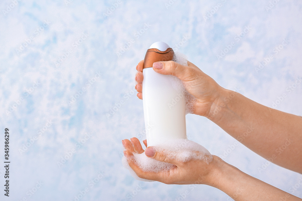 Female hands with shower gel on light background