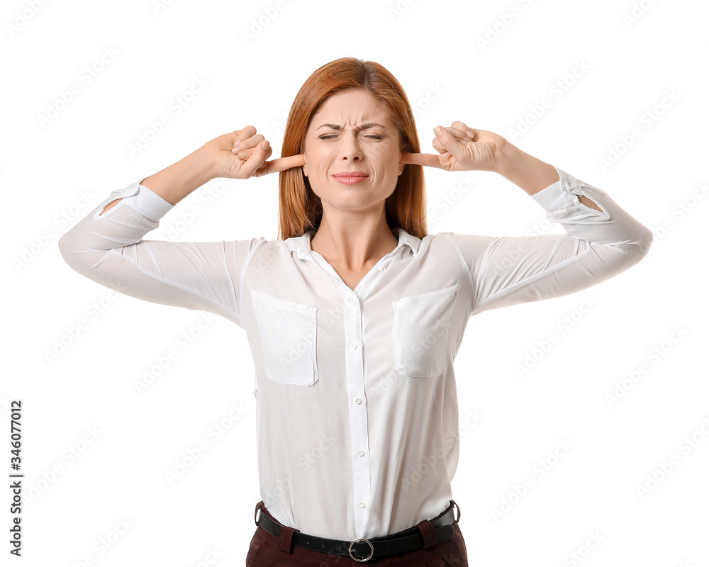 Young woman suffering from loud noise on white background