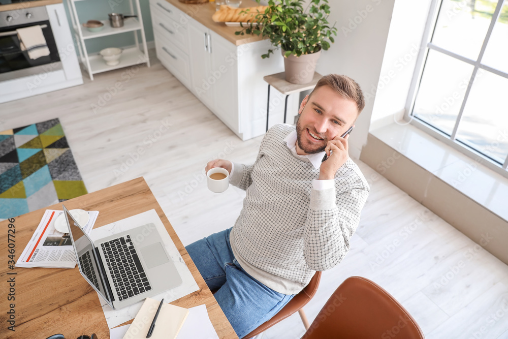 Young man with laptop and mobile phone working at home