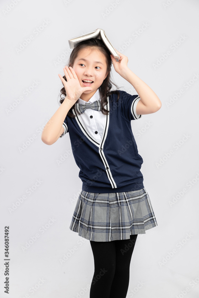 Asian primary  school girls in school uniforms on a gray background