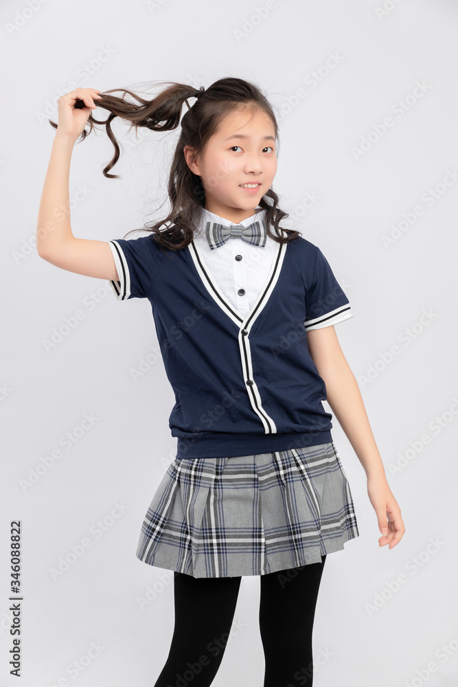 灰色背景下穿着校服的亚洲小学女生