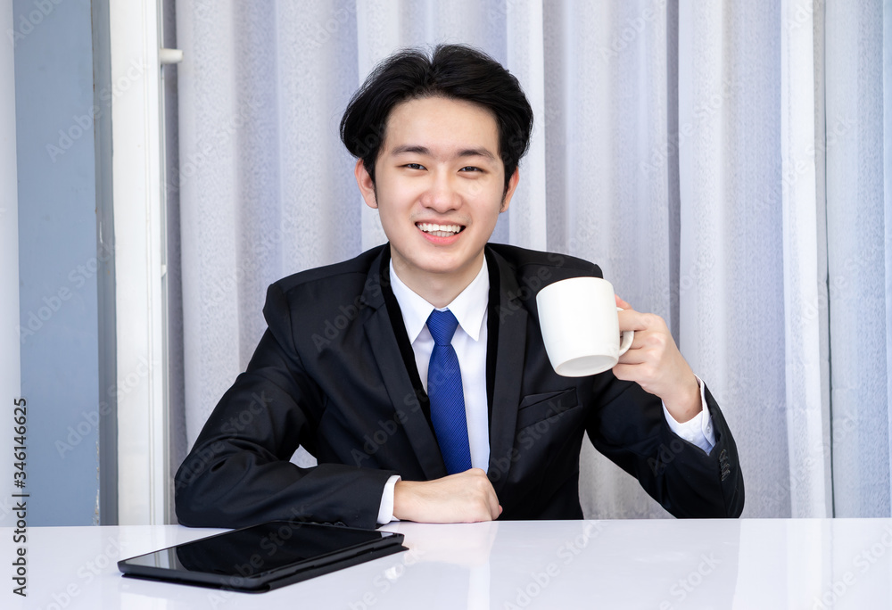 Asian business man dringking coffee wearing suit, enjoying watching educational webinar on laptop or