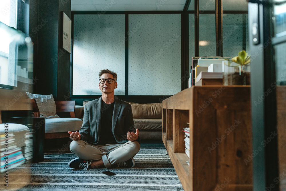 Businessman meditating in lotus pose