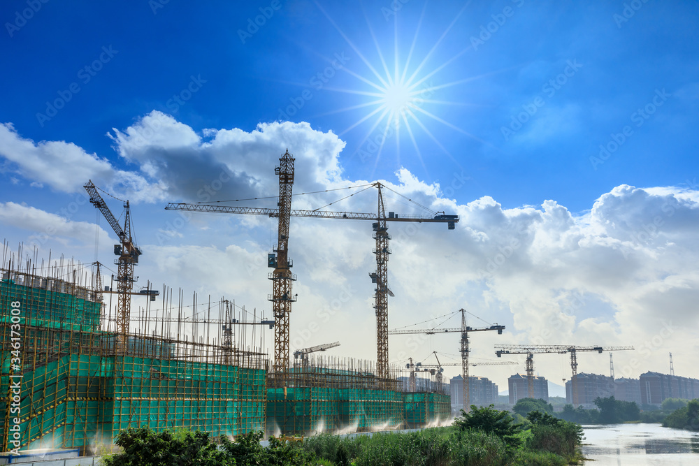 Crane and building construction site against blue sky.