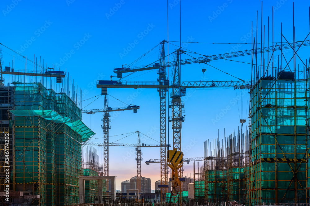 Tower crane and building construction site silhouette at sunrise.