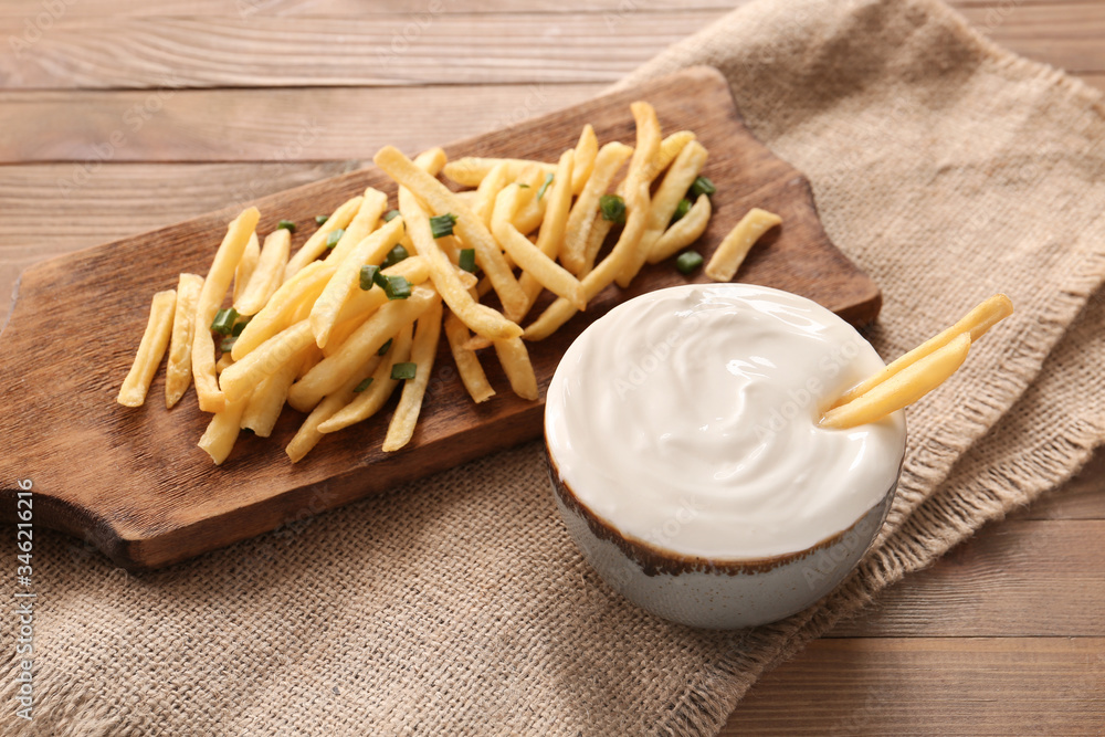 Bowl with tasty sour cream and french fries on table