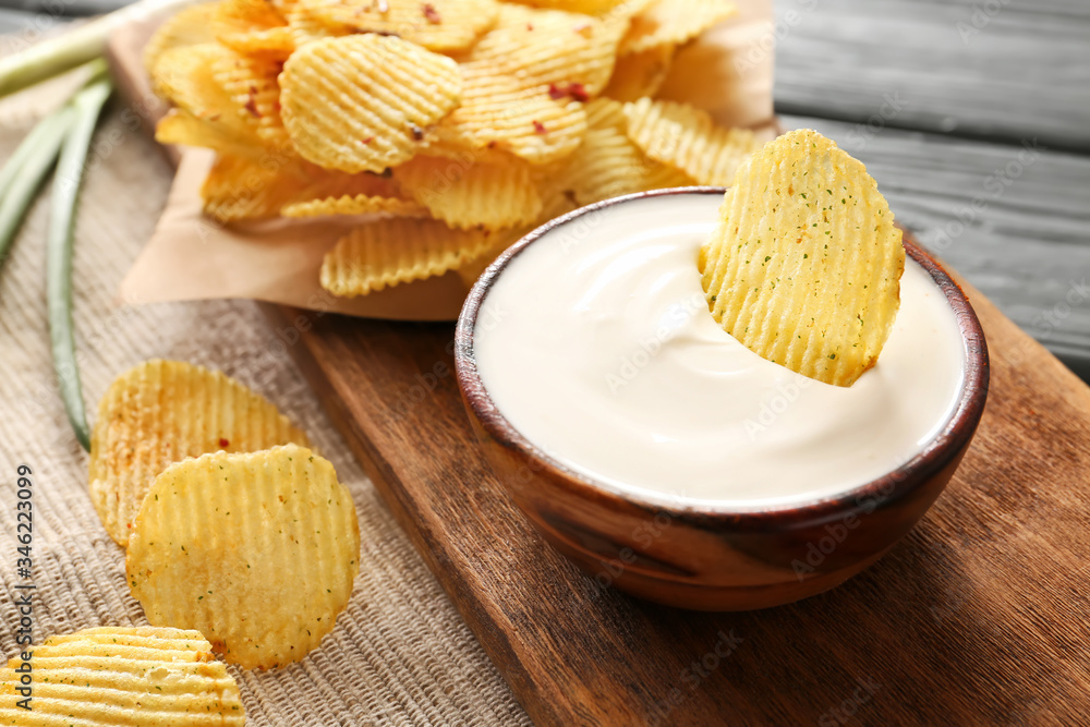 Bowl with tasty sour cream and potato chips on table