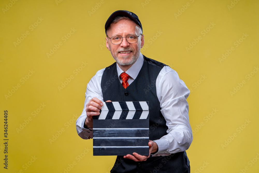 Senior handsome man holding a cinema clapper. Man wearing suit with no jacket. Person isolated again