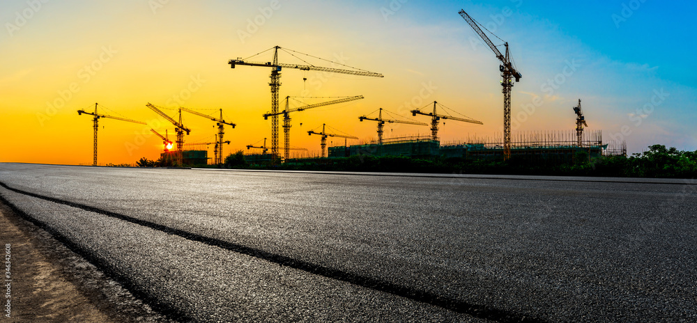 Empty asphalt road and construction site landscape at sunrise.