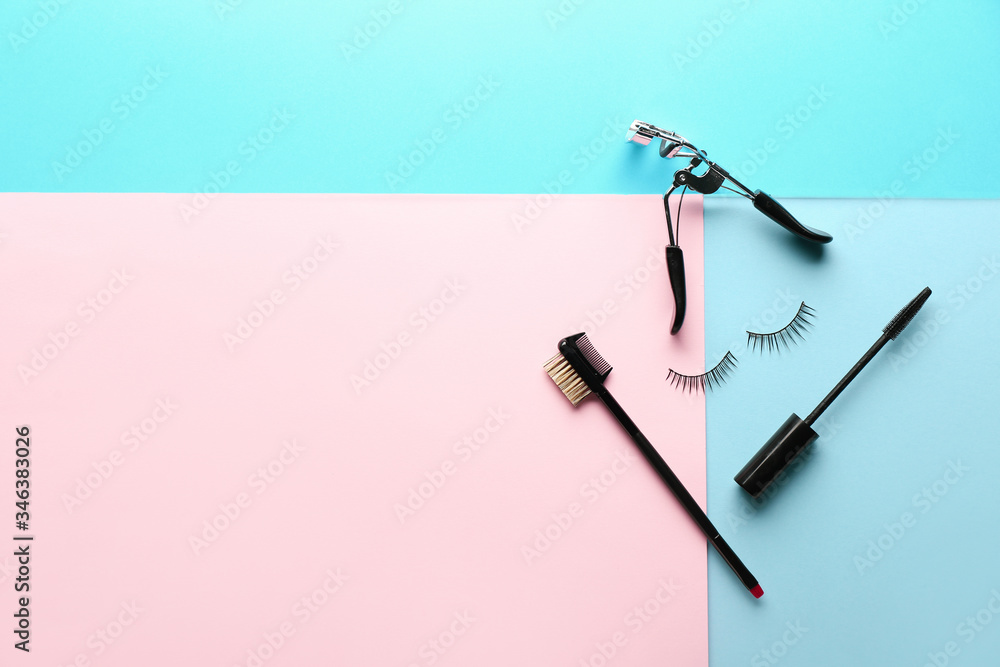 Mascara, brush, fake eyelashes and curler on color background