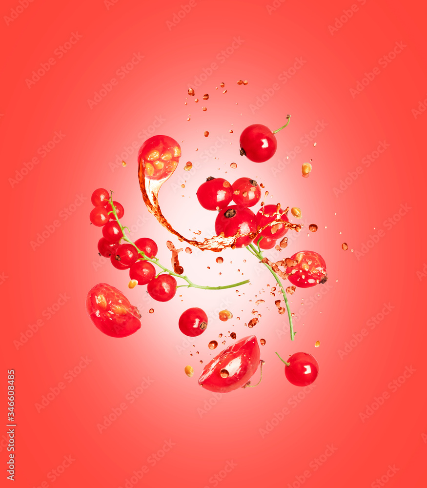 Whole and sliced berries of red currant with splashes of juice on a red background