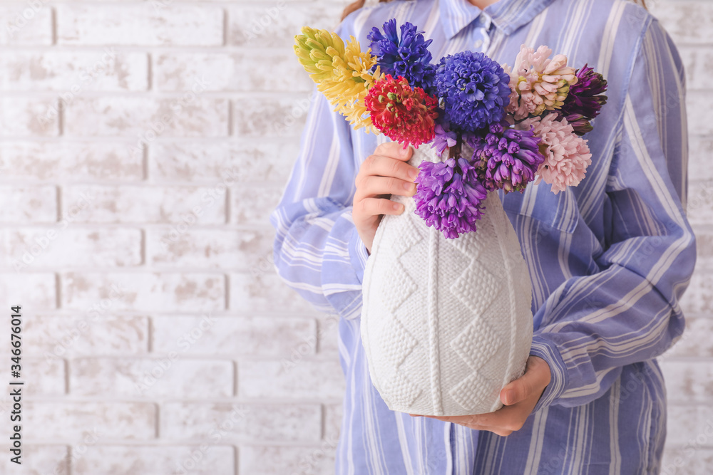 Woman with beautiful hyacinth flowers on brick background, closeup