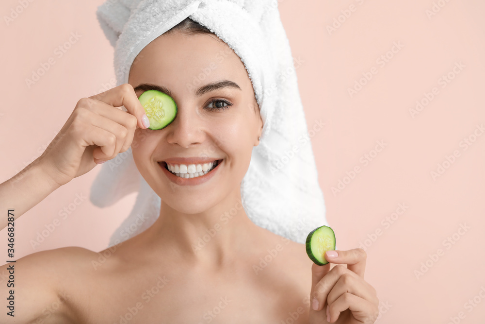 Beautiful young woman with cucumber slices on color background