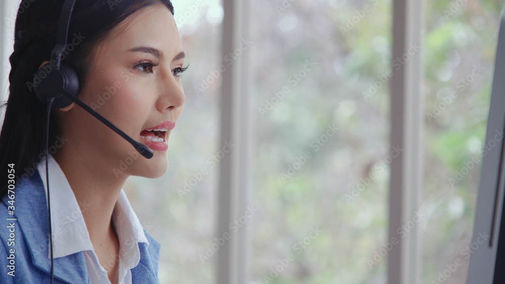 Customer support agent or call center with headset works on desktop computer while supporting the cu