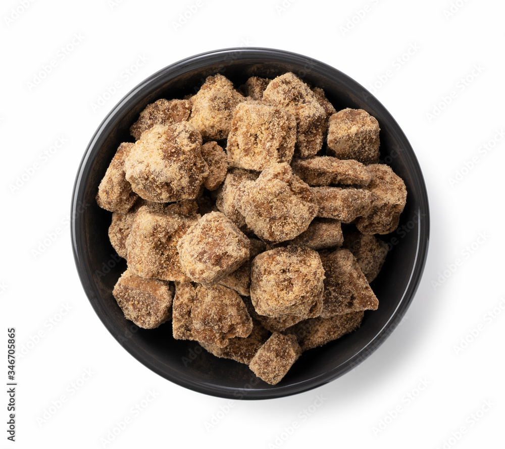 A birds-eye view of a block of brown sugar in a black container placed on a white background