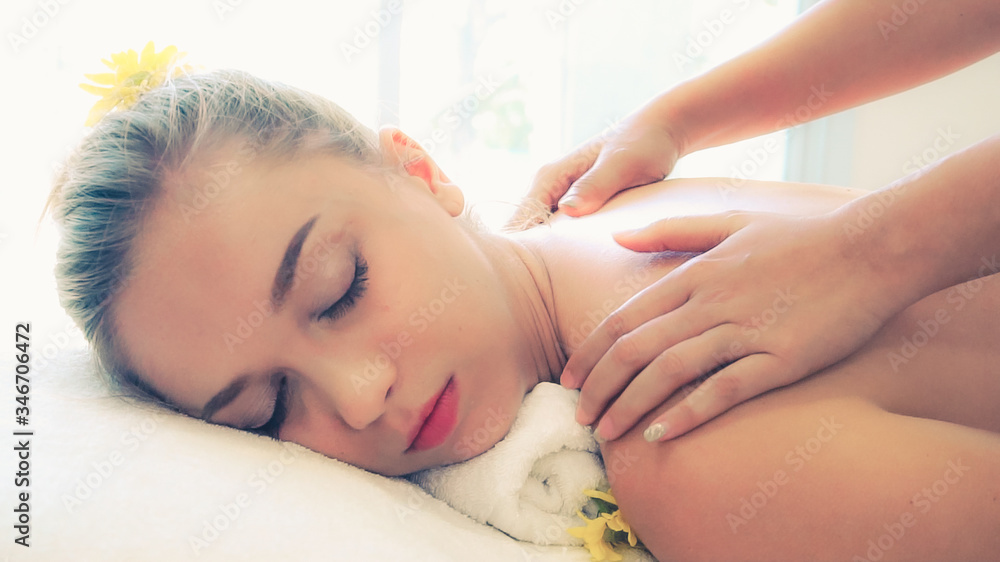 Relaxed woman getting back massage in luxury spa with professional massage therapist. Wellness, heal