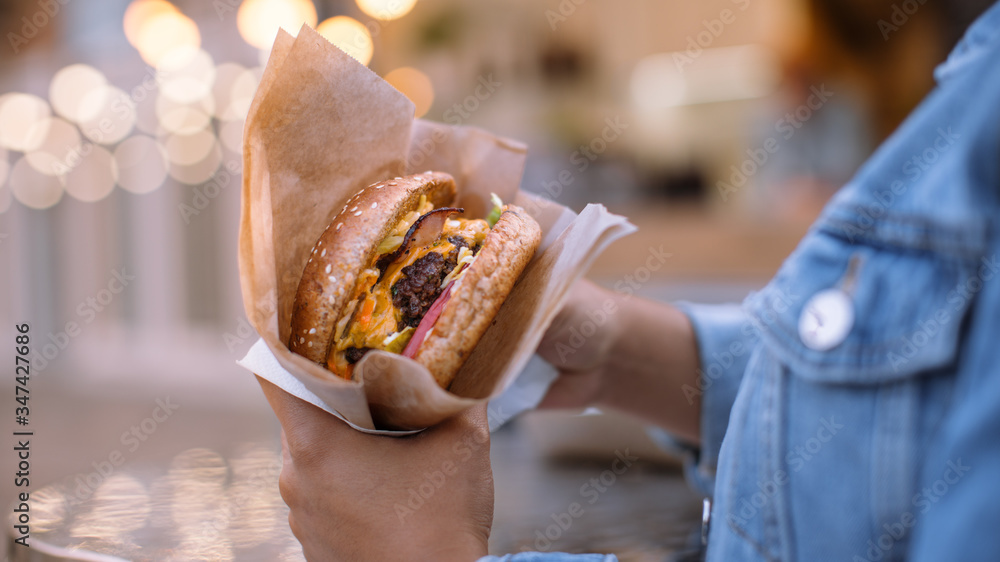 Close Up Shot of a Tasty Burger. Young Person is Holding Burger with Flaming Hot Grounded Beef Patty