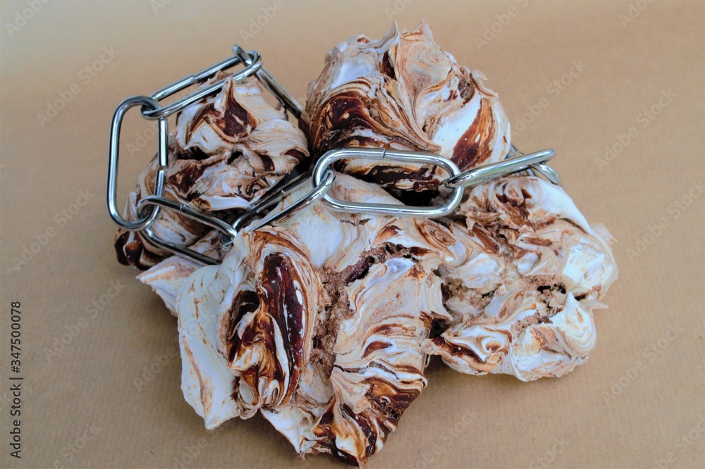 Composition of homemade french meringue with chocolate and metal chain on a light background