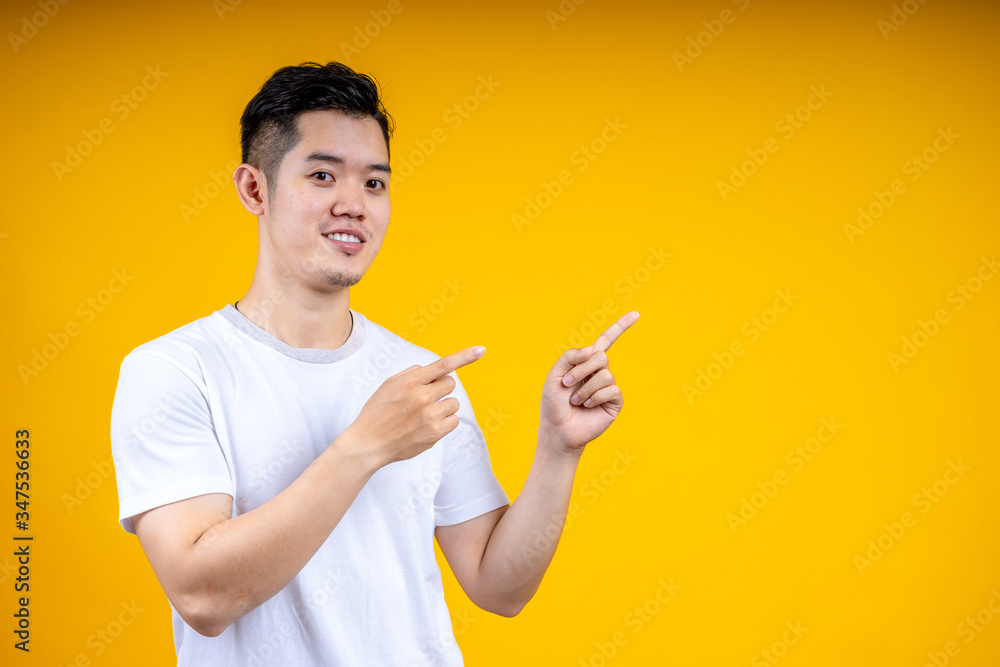 Asian man posing isolated on yellow orange background, studio portrait. People emotions lifestyle co