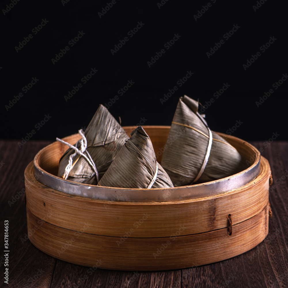 Zongzi - Chinese rice dumpling zongzi in a steamer on wooden table black retro background for Dragon