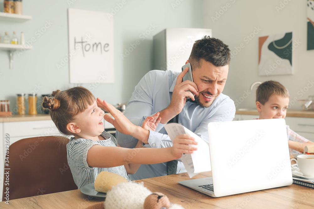 Little children keeping father from his work at home