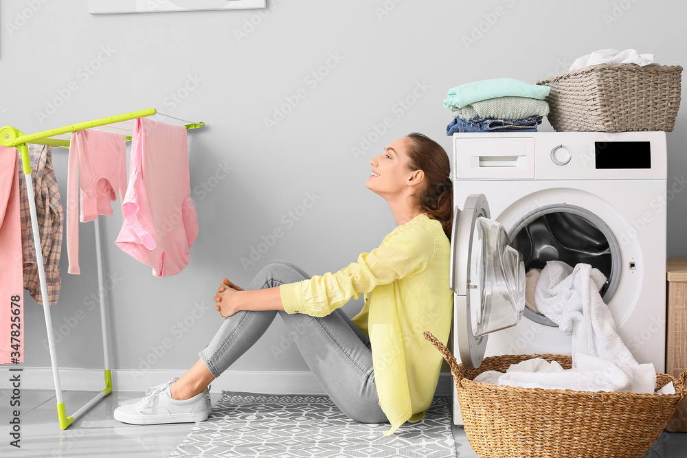 Young woman doing laundry in bathroom