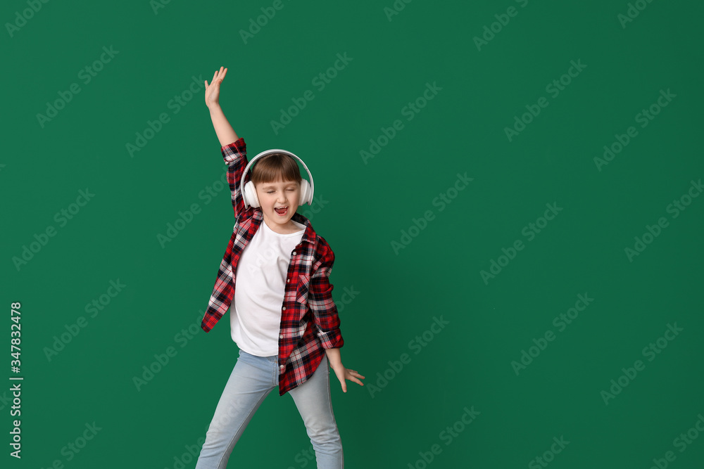 Cute little girl dancing and listening to music against color background