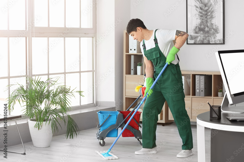 Male janitor mopping floor in office