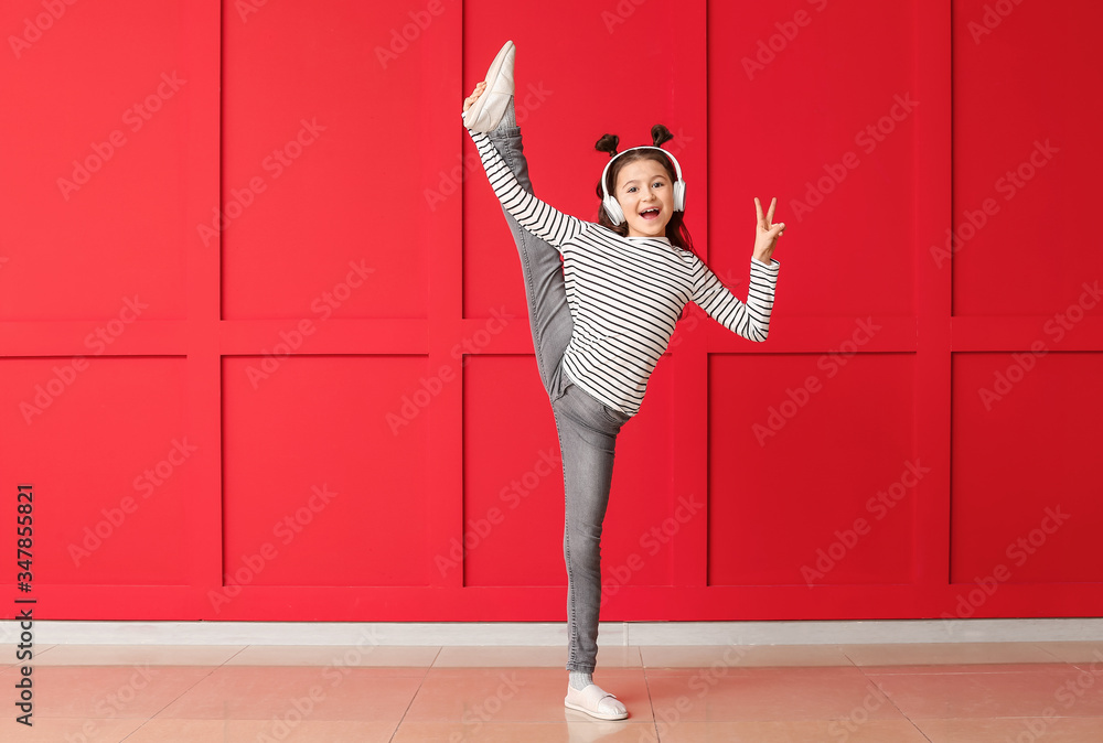 Cute dancing girl near color wall