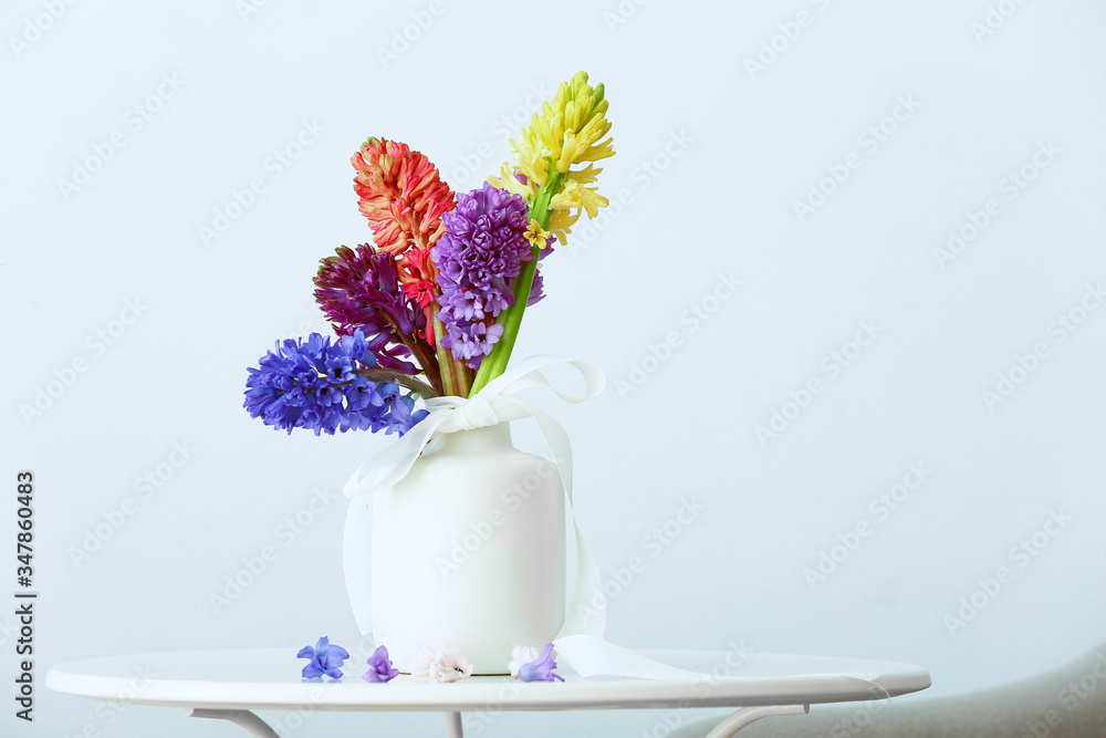 Vase with beautiful hyacinth flowers on table against grey background