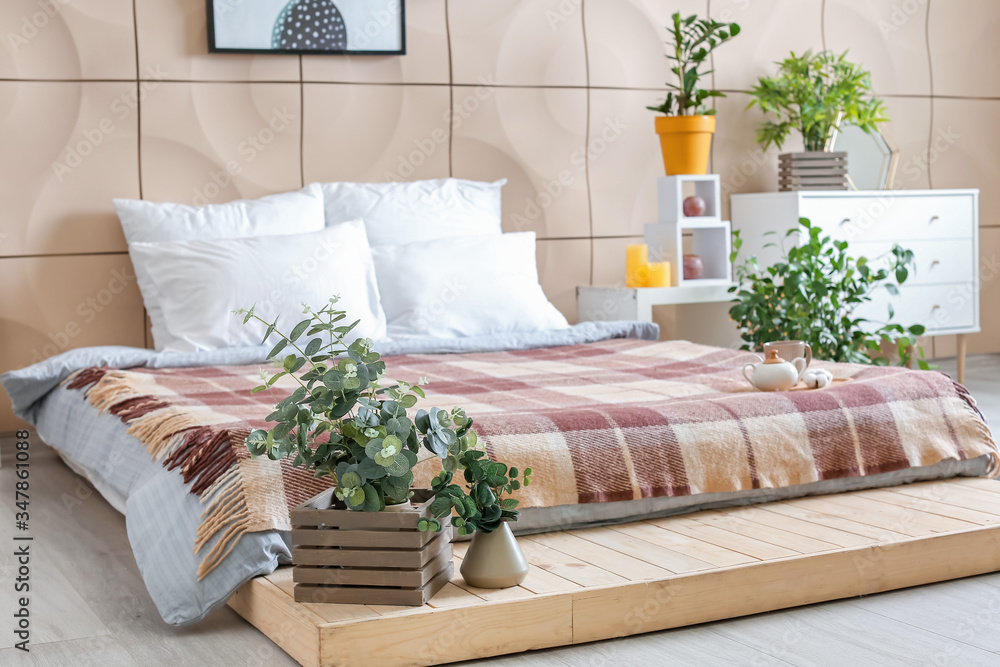 Stylish interior of bedroom with green houseplants