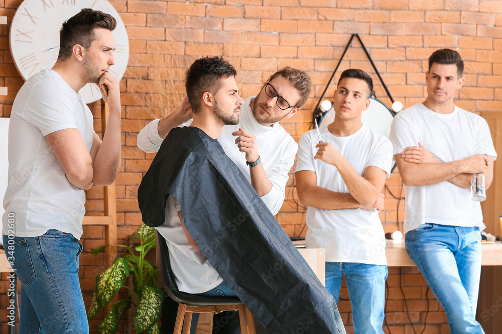 Professional hairdresser teaching young men in salon