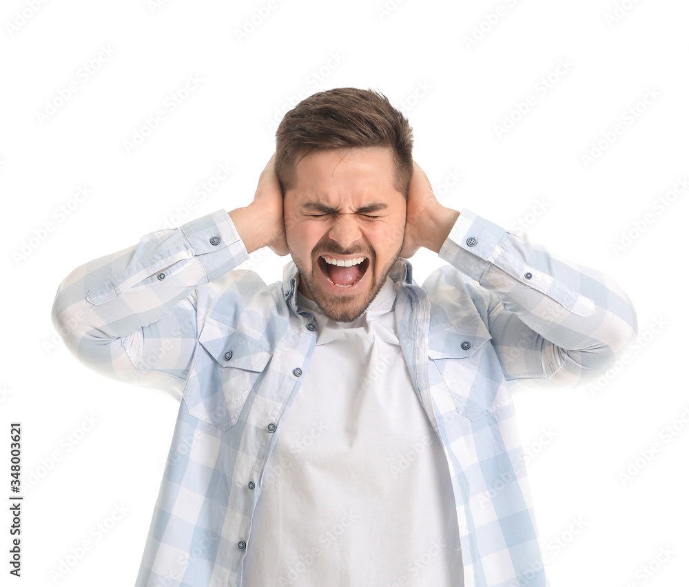 Young man suffering from loud noise on white background