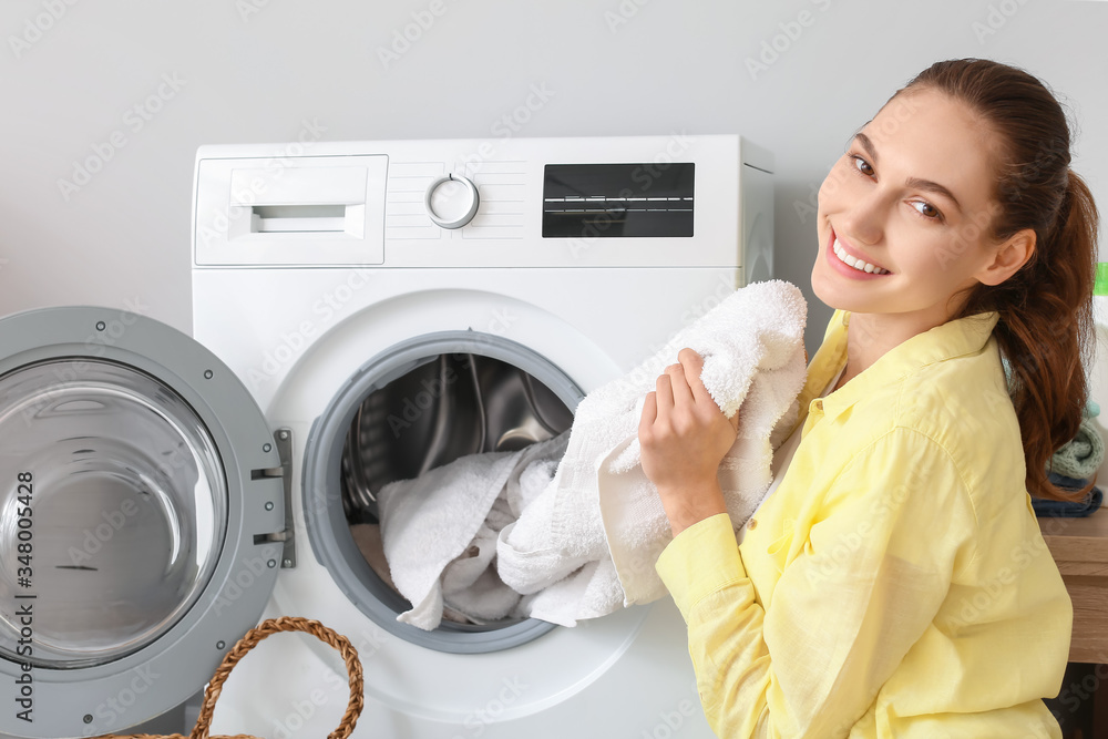 Young woman doing laundry in bathroom