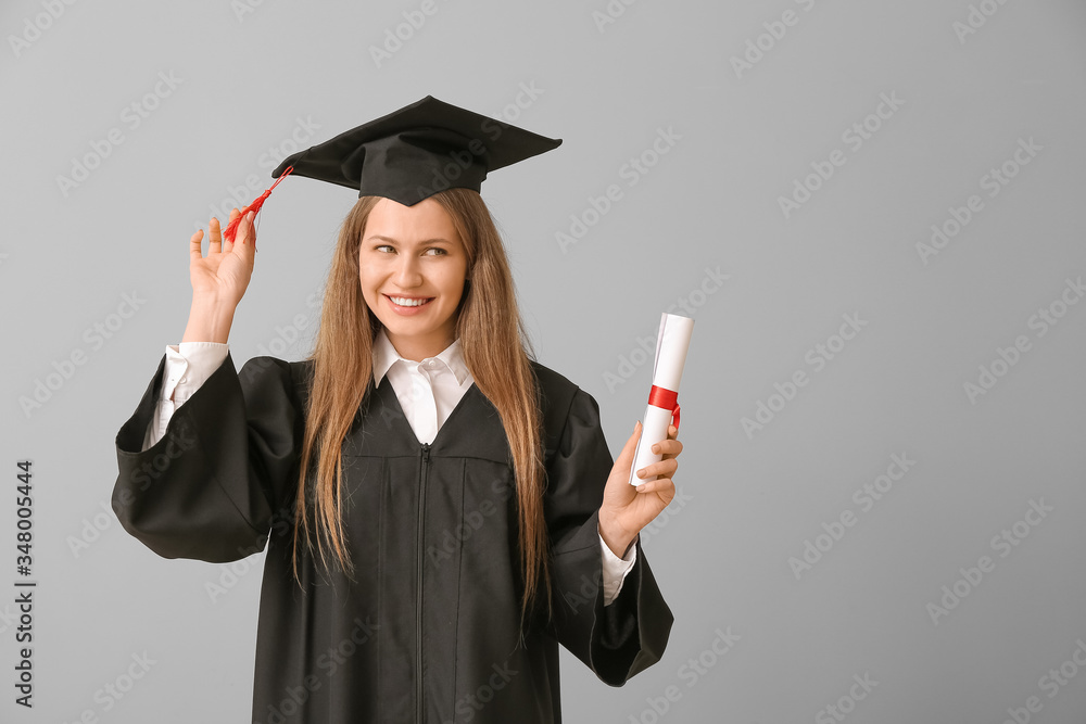 Female graduating student with diploma on light background