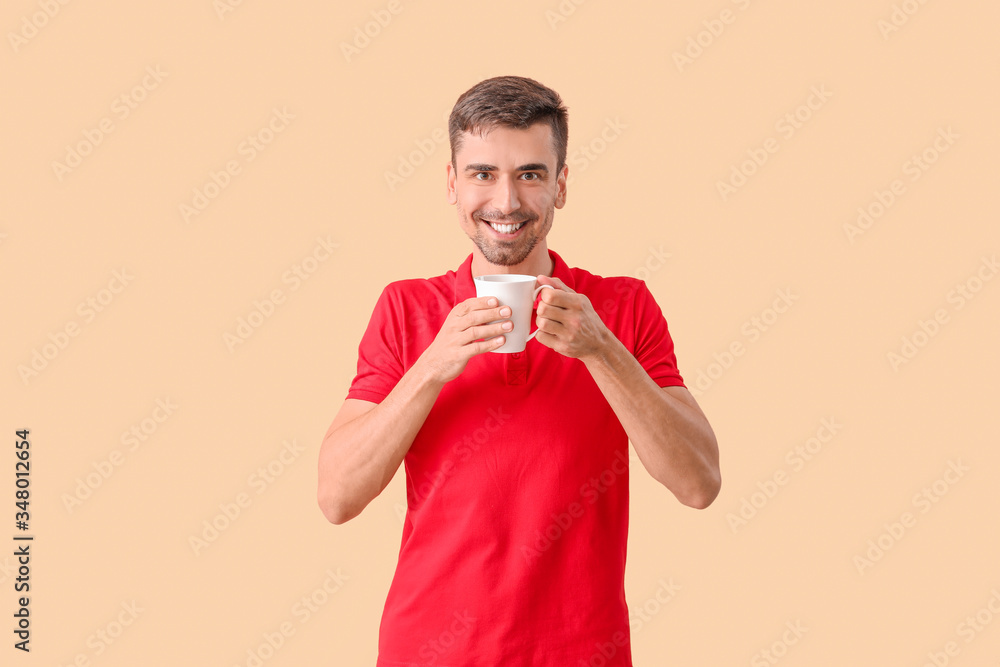 Young man with cup of hot coffee on color background