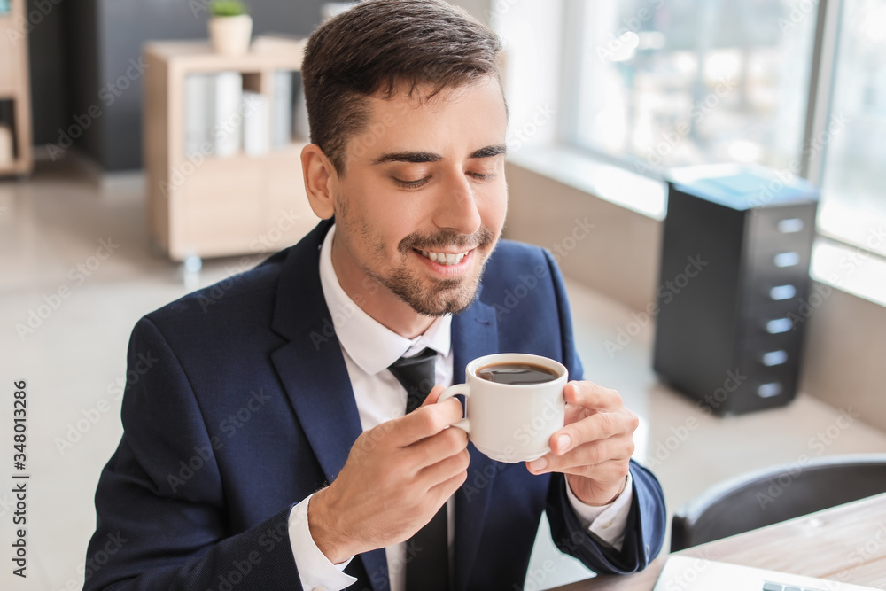 办公室里喝着一杯热咖啡的年轻商人