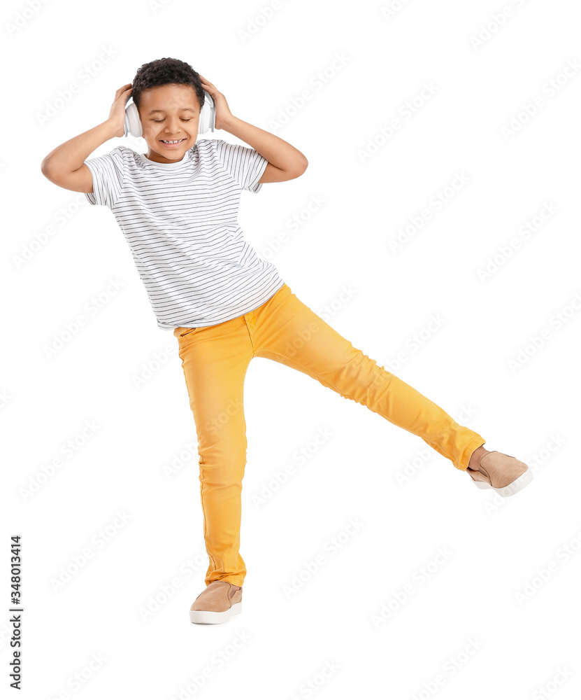 Little African-American boy listening to music and dancing against white background