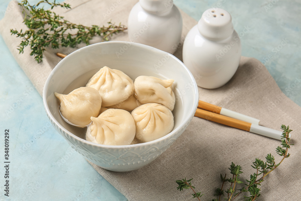 Bowl with tasty dumplings on color background