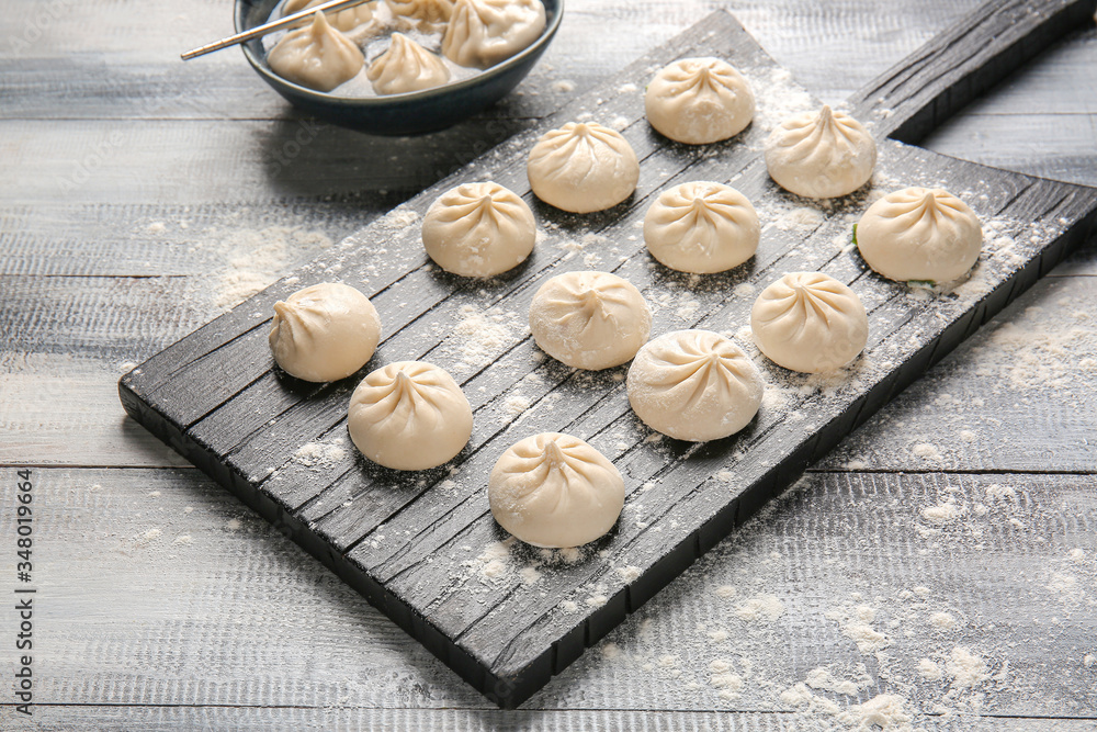 Board with raw dumplings on table