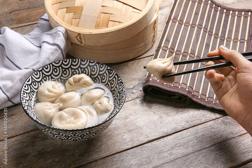 Woman eating tasty dumplings from bowl