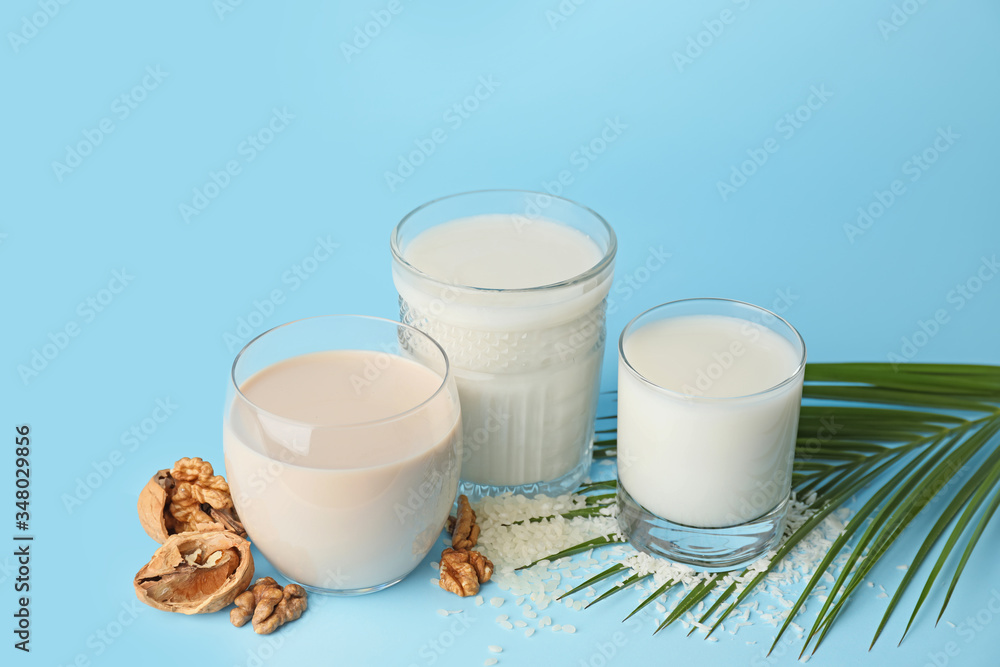 Glasses of different milk on color background