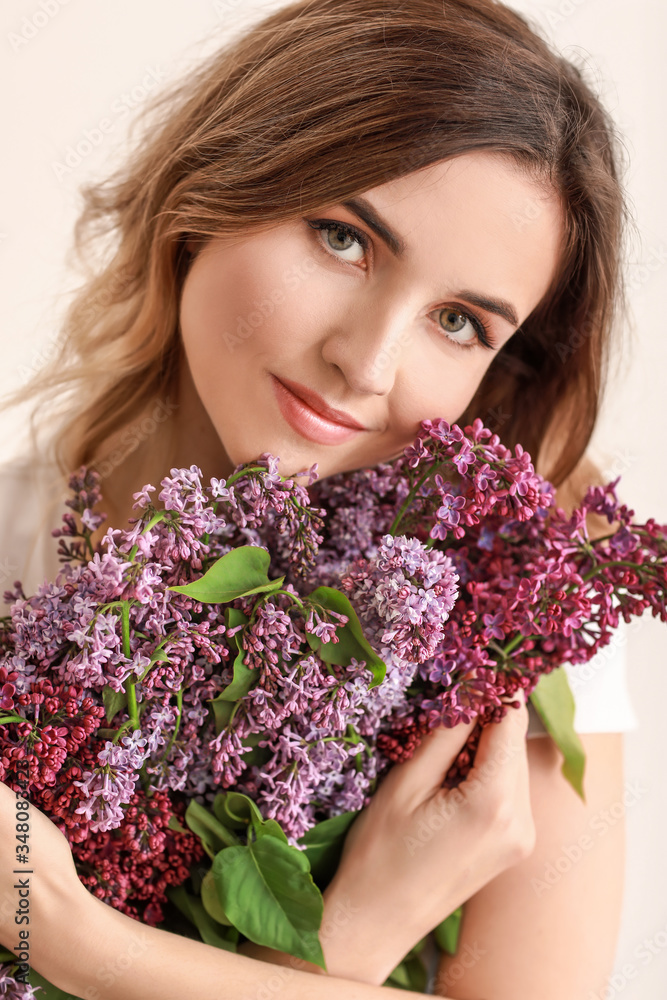 Beautiful young woman with bouquet of lilac flowers on white background